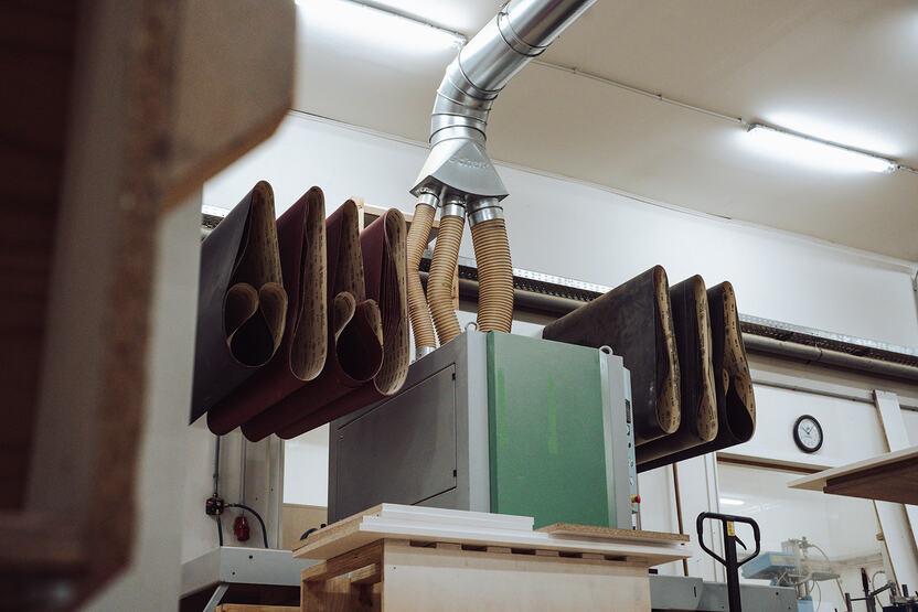 Maschinenhalle im Zentrum des Bildes befindet sich eine Schleifmaschine mit dazugehörigem Schmirgelpapier
