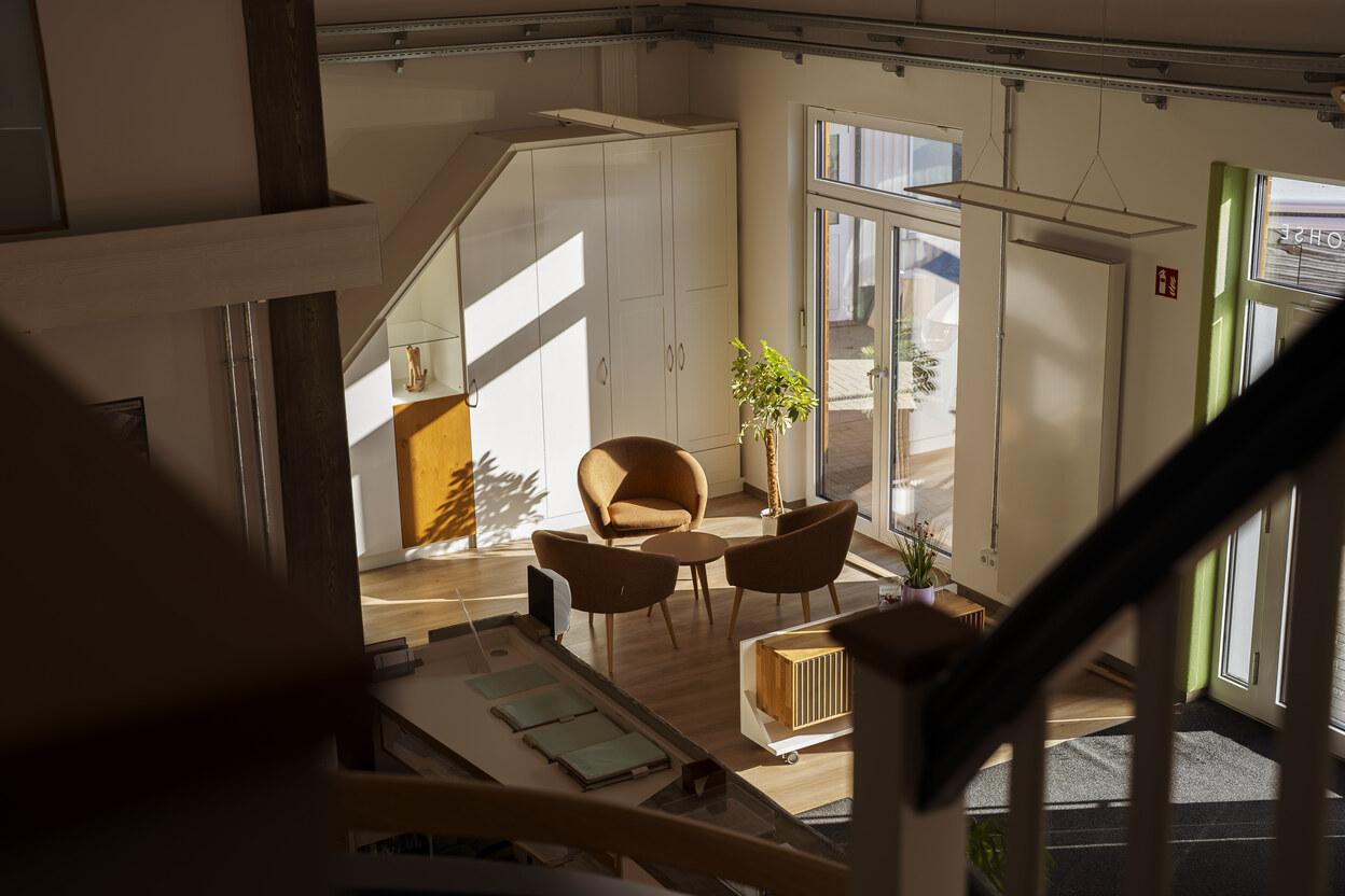 Beratungsbereich Möbel und Innenausbau runder Tisch mit Sesseln zur Planung von Möbel und Innenausbauten im Hintergrund befindet sich ein weißer Dachschrägenschrank in einem lichtdurchfluteten IDEEN REICH